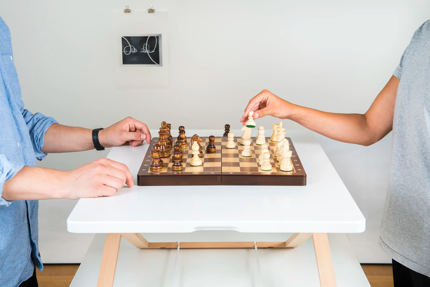 Two people playing chess on a Freedesk Desk Riser, showcasing a versatile and adjustable workspace.