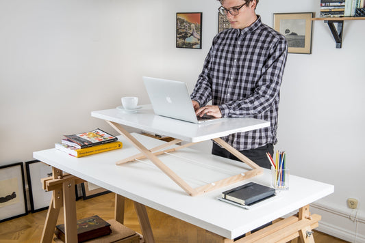 A young man working at a laptop on a Freedesk Desk Riser.