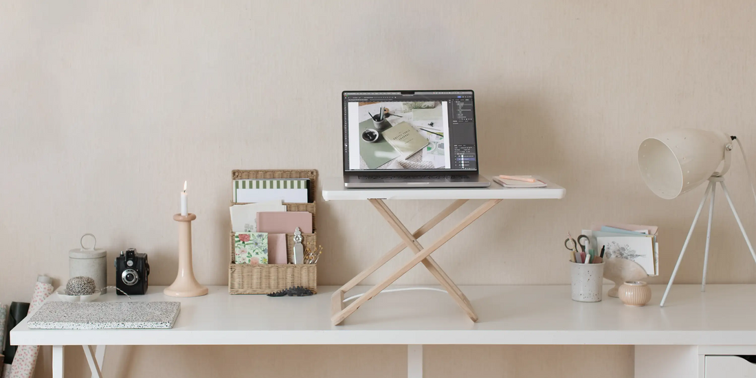 Freedesk Desk Riser i uppfällt läge på ett skrivbord i ett ljust hemmakontor.