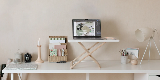 Freedesk Desk Riser i uppfällt läge på ett skrivbord i ett ljust hemmakontor.