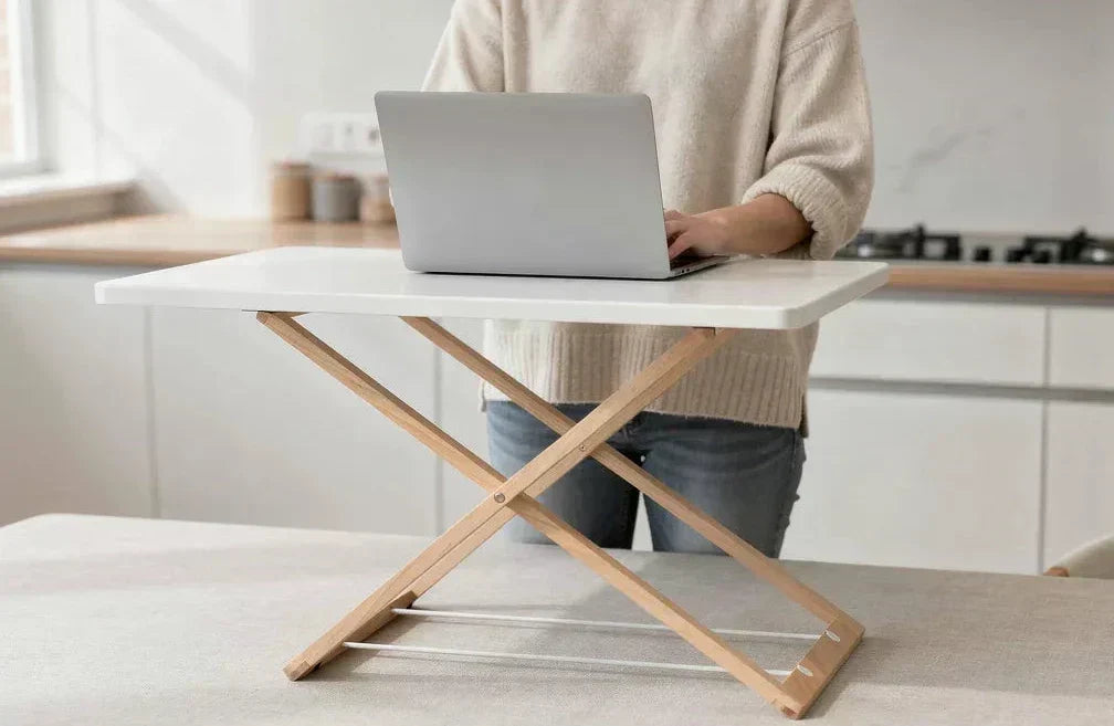 Person alternating between sitting and standing at desk riser in Scandinavian home office.