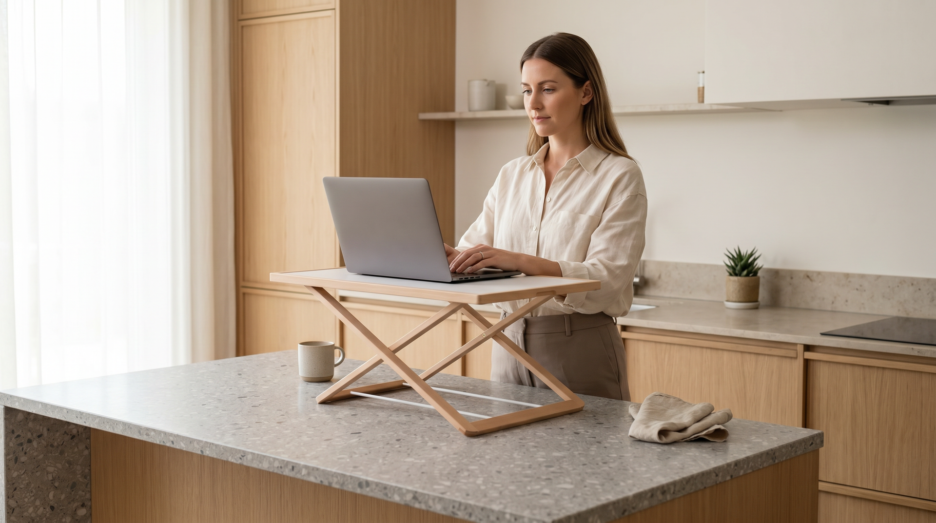 A woman working with a laptop on a Freedesk Desk Riser in a kitchen..