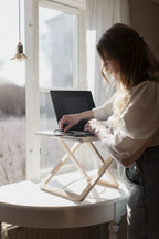 Freedesk Desk Riser Original Compact placed in a sunny window nook with laptop