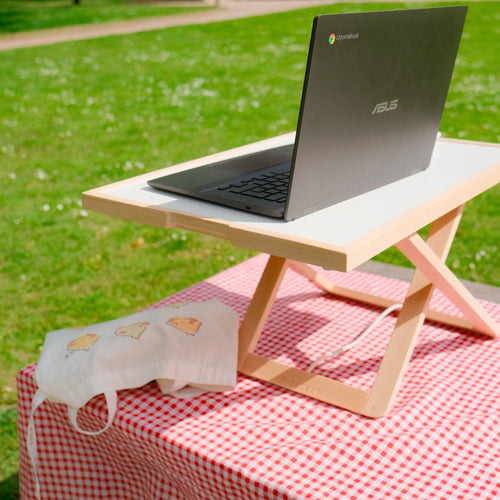 Freedesk Desk Riser Light Compact on table in a park.