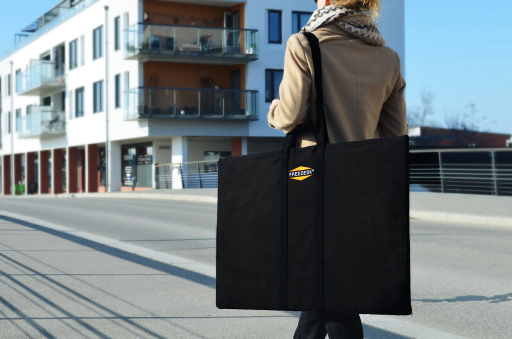 A person carrying a Freedesk Carrying Case Large while walking in an urban environment.