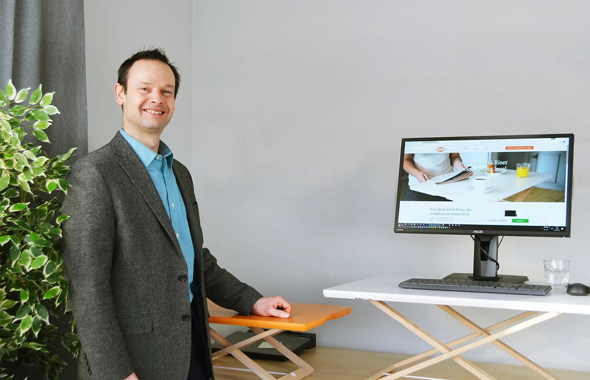Stefan Westergard, Gründer von Freedesk, steht neben einem Freedesk Desk Riser in einer Büroumgebung.